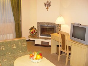 A living room with a fireplace, television, and a fruit bowl on a table. - Hotel Orphey Bansko (Bansko)
