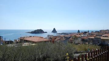 Un pueblo costero con edificios a lo largo de la costa, cielo despejado y afloramientos rocosos en el mar.