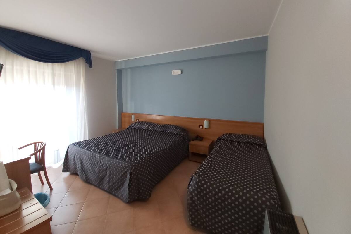 A room with two beds, a wooden headboard, a chair, and a small table.