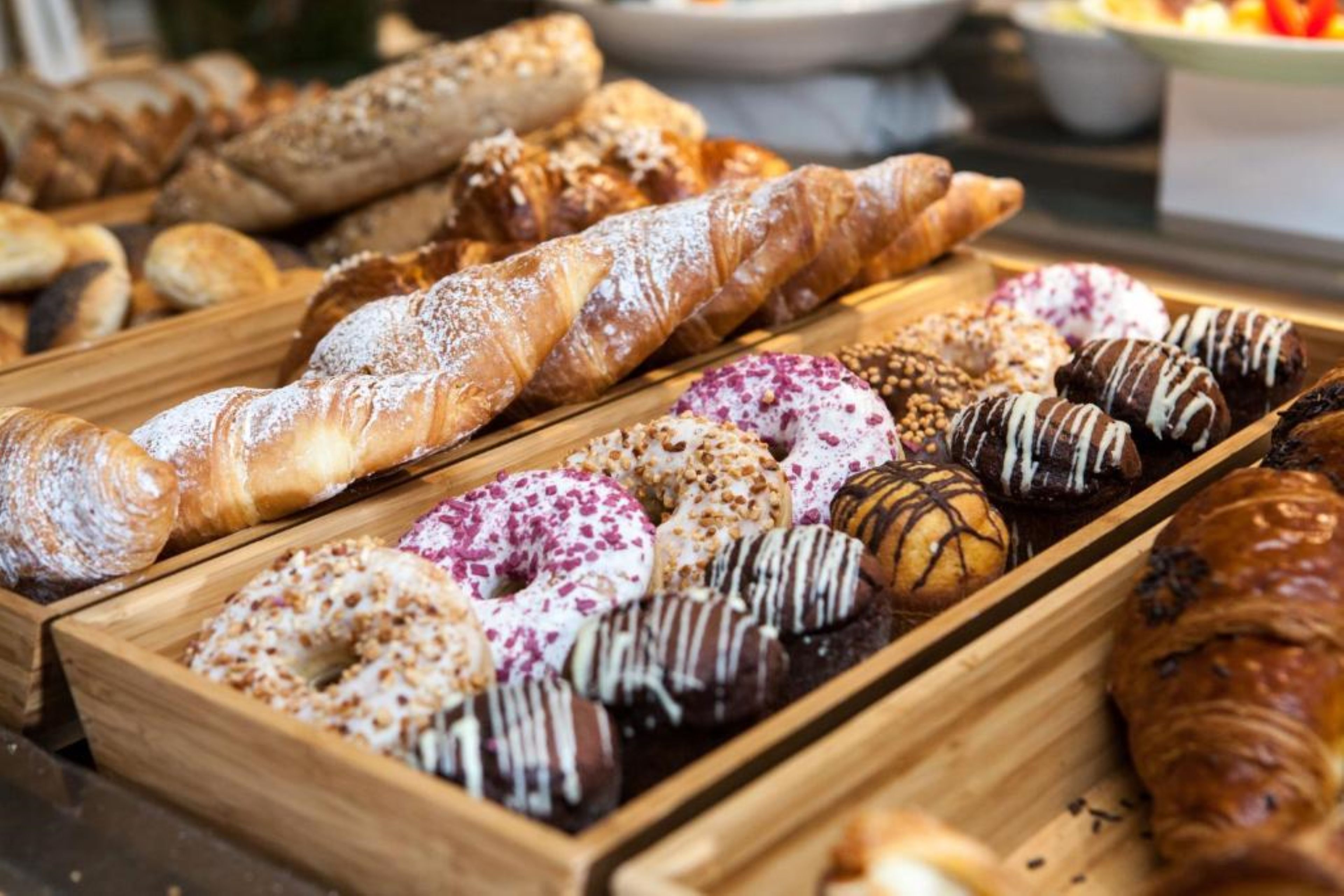 Variedad de productos de repostería, como pasteles y donas, en bandejas de madera.