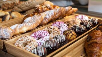 Variedad de productos de repostería, como pasteles y donas, en bandejas de madera.