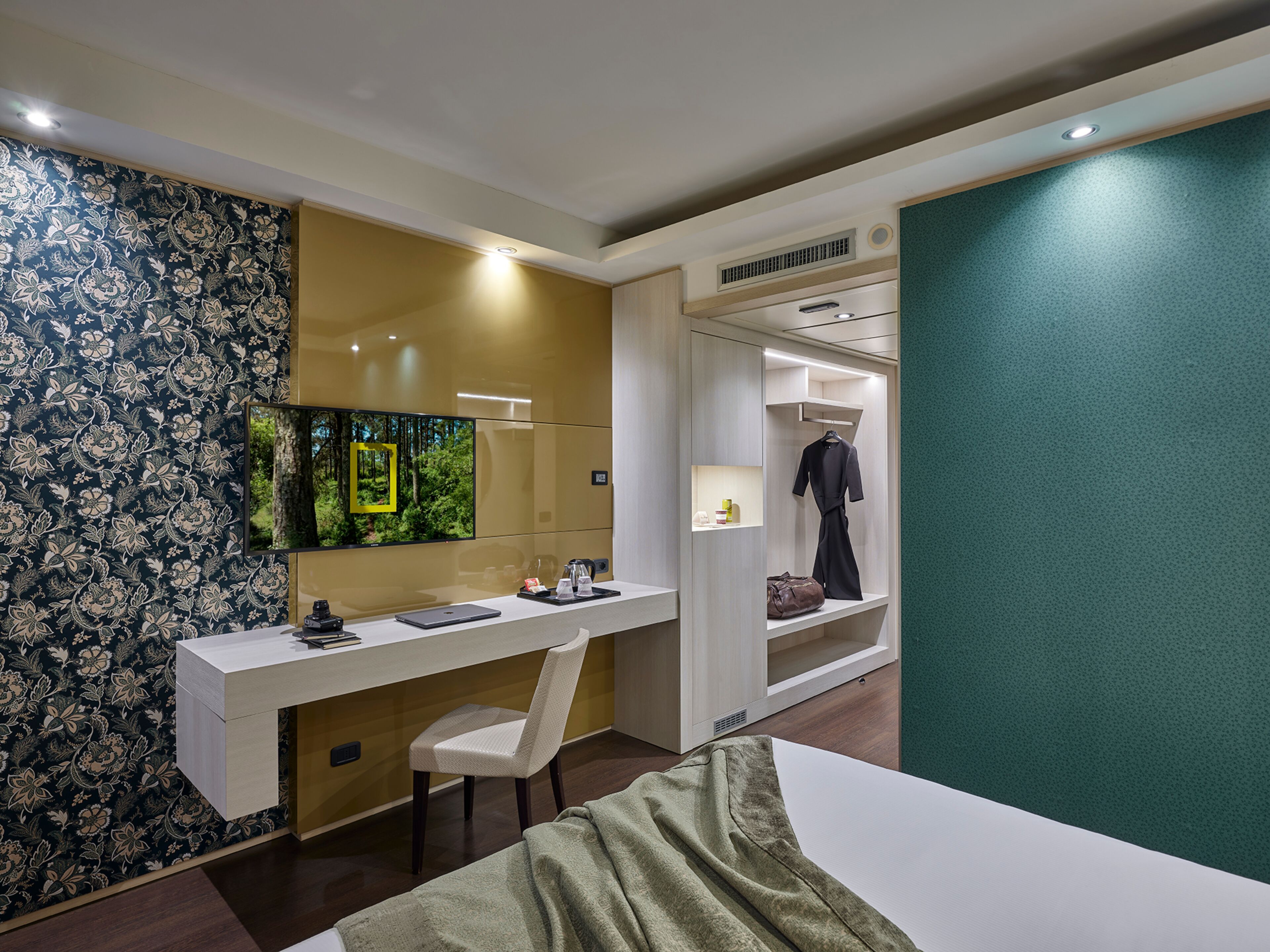 Een moderne hotelkamer met een bureau, stoel en een inloopkast.