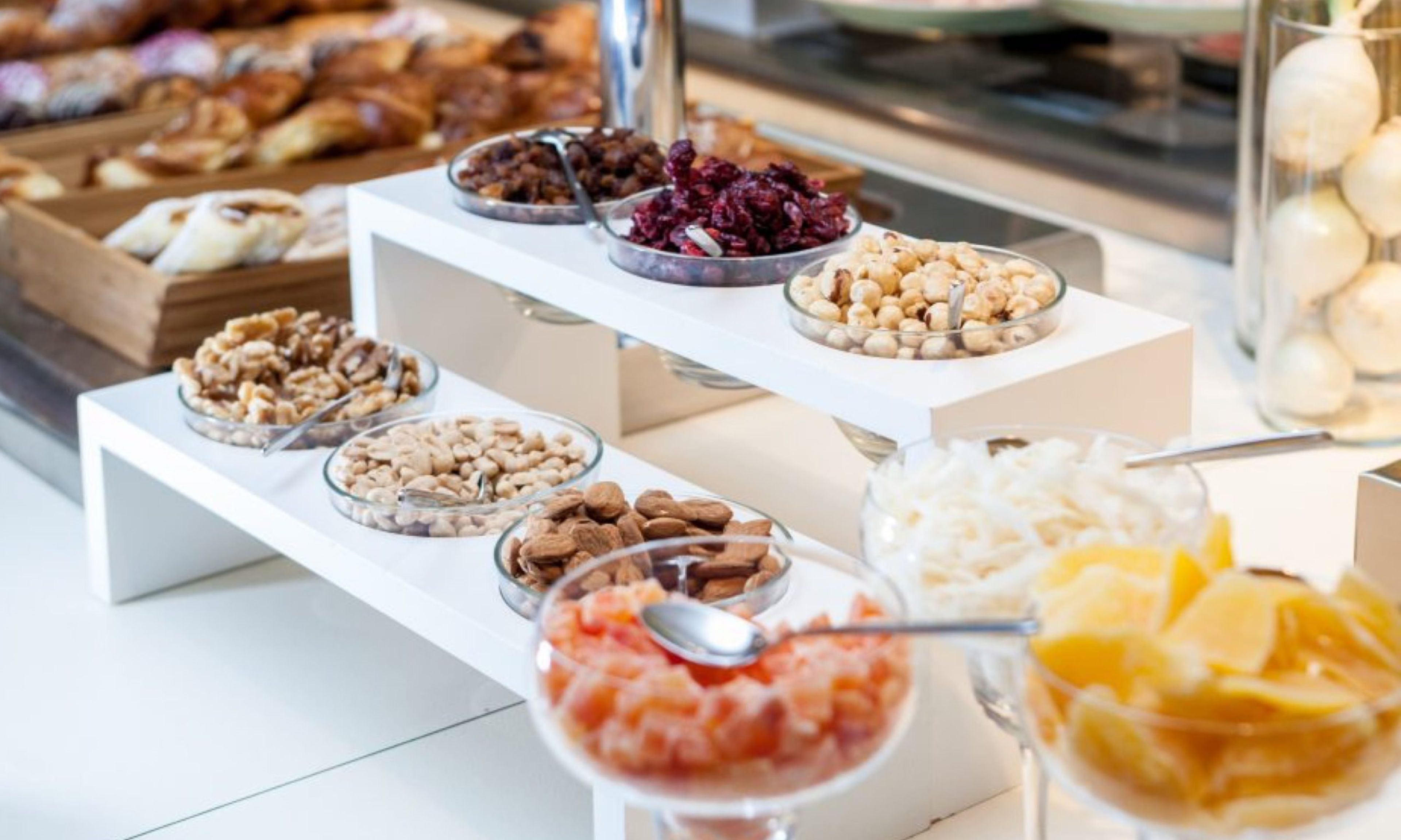 Un buffet con diversi cibi, tra cui noci, frutta secca e una ciotola che sembra contenere insalata di frutta.