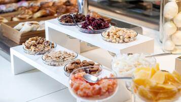 Un buffet con diversi cibi, tra cui noci, frutta secca e una ciotola che sembra contenere insalata di frutta.