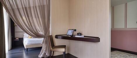 Una habitación de hotel moderna con una cama, un escritorio con una computadora portátil y una cámara, una silla y un ventanal con cortinas.