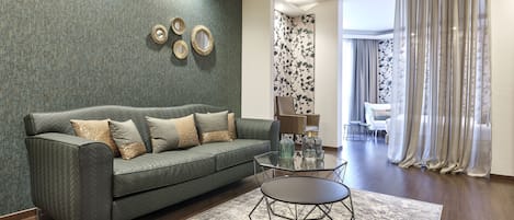 A modern living room with a green sofa, a glass coffee table, and a patterned rug.