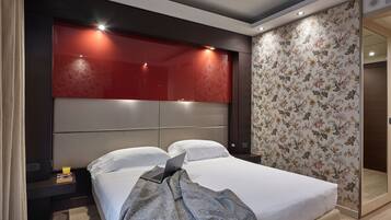 Una habitación de hotel moderna con una cama grande, una mesita de noche, una computadora portátil y una pared de acento roja.
