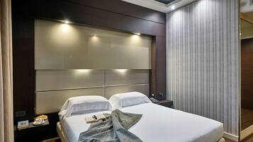 Una habitación de hotel moderna con una cama grande, mesitas de noche y un amplio ventanal con cortinas.