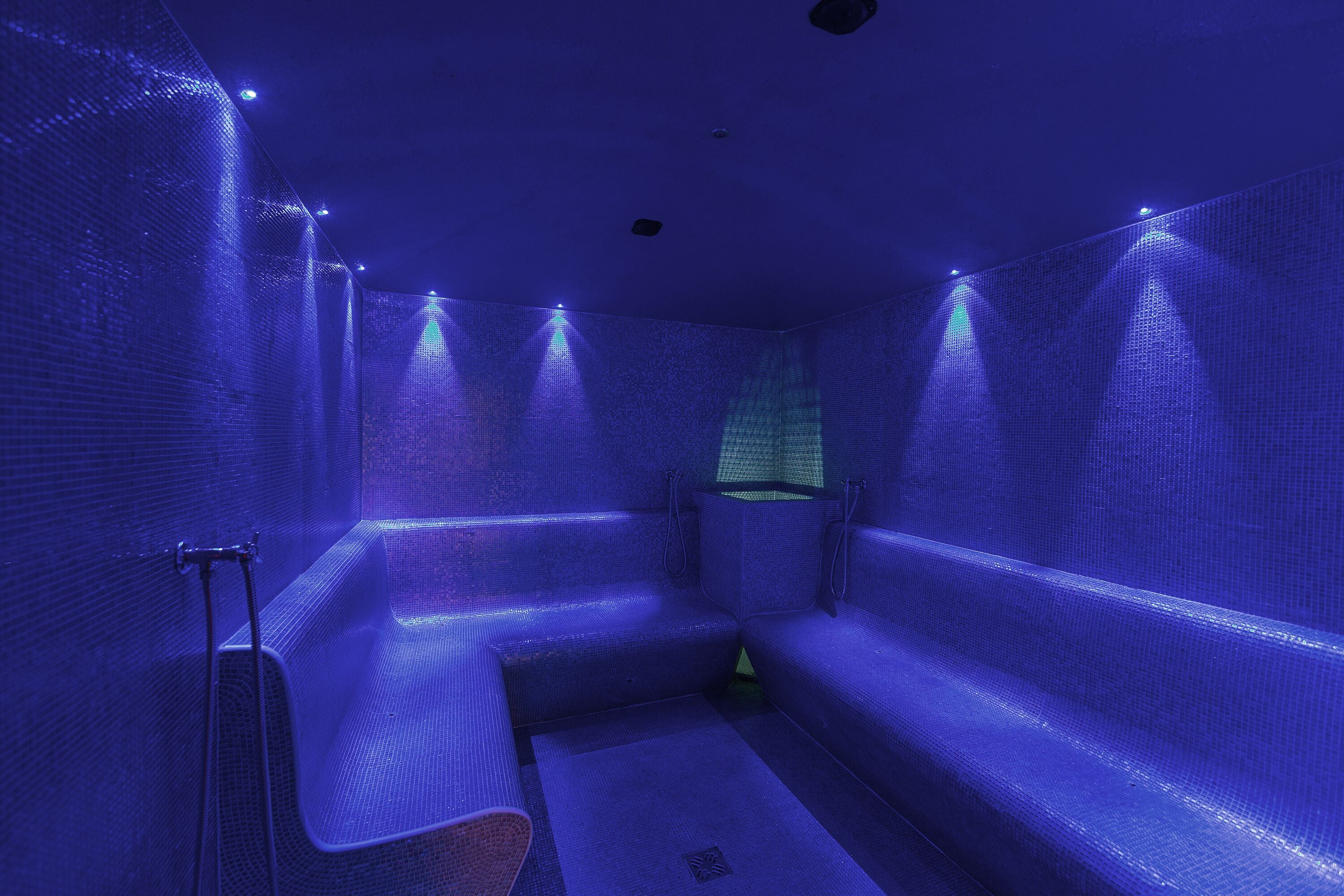 Una stanza con un design illuminazione blu particolare, un'area salotto e una piccola finestra.