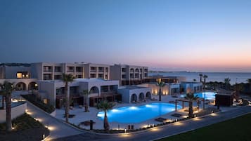 A resort with a swimming pool, multiple balconies, and a view of the sea.