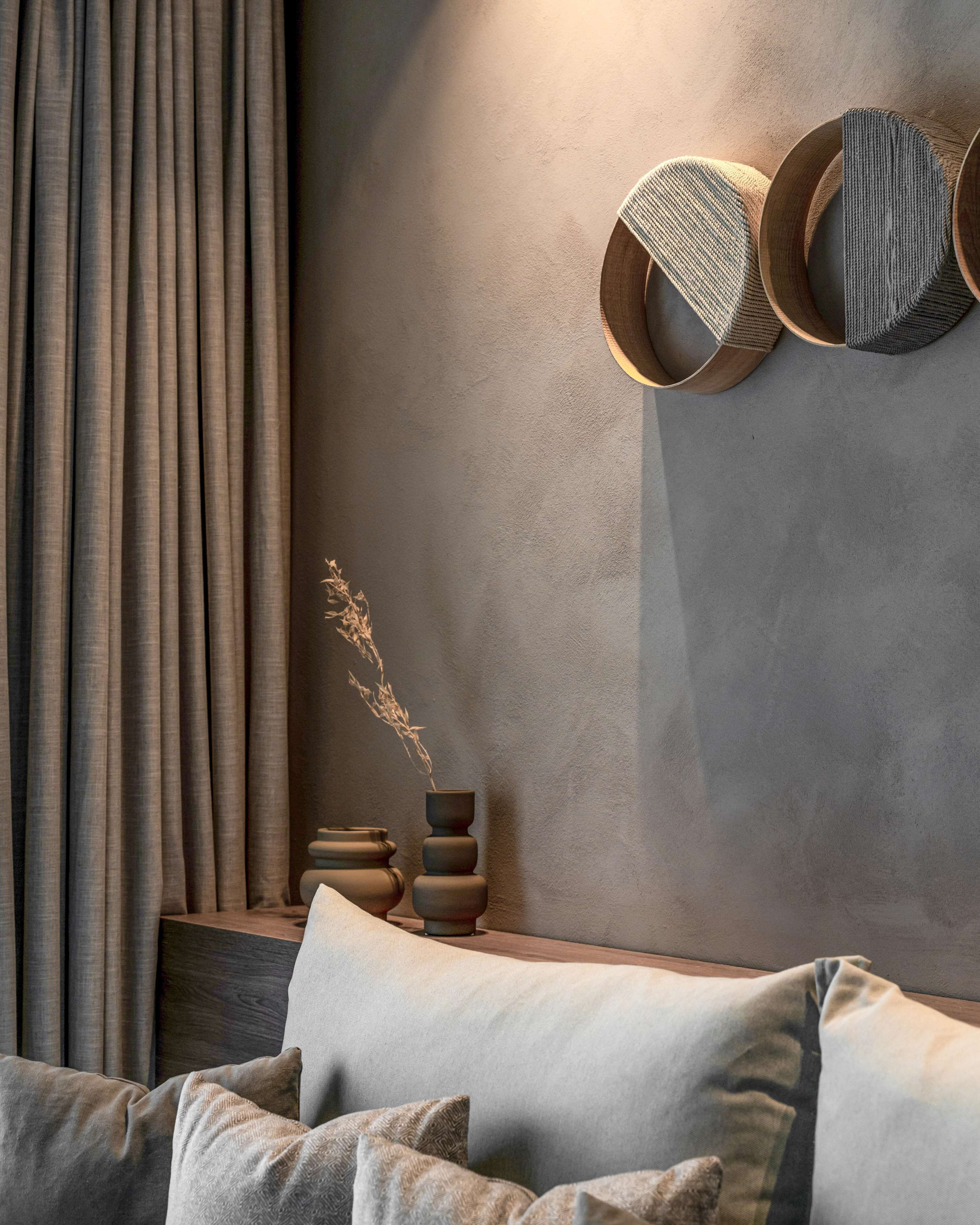 Ein modernes Interieur mit einer Couch, Kissen, einem an der Wand befestigten Regal mit Dekoration und Vorhängen.