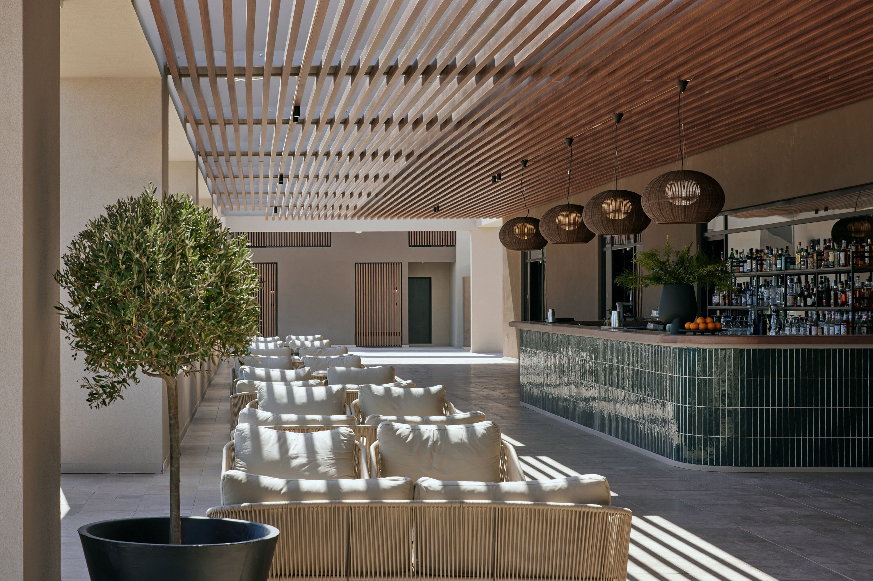 A modern lounge area with a row of sofas and a bar with a tiled backsplash.
