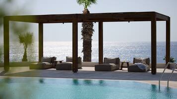 Ein Poolbereich mit einer Holzpergola, Liegestühlen und einer Palme.