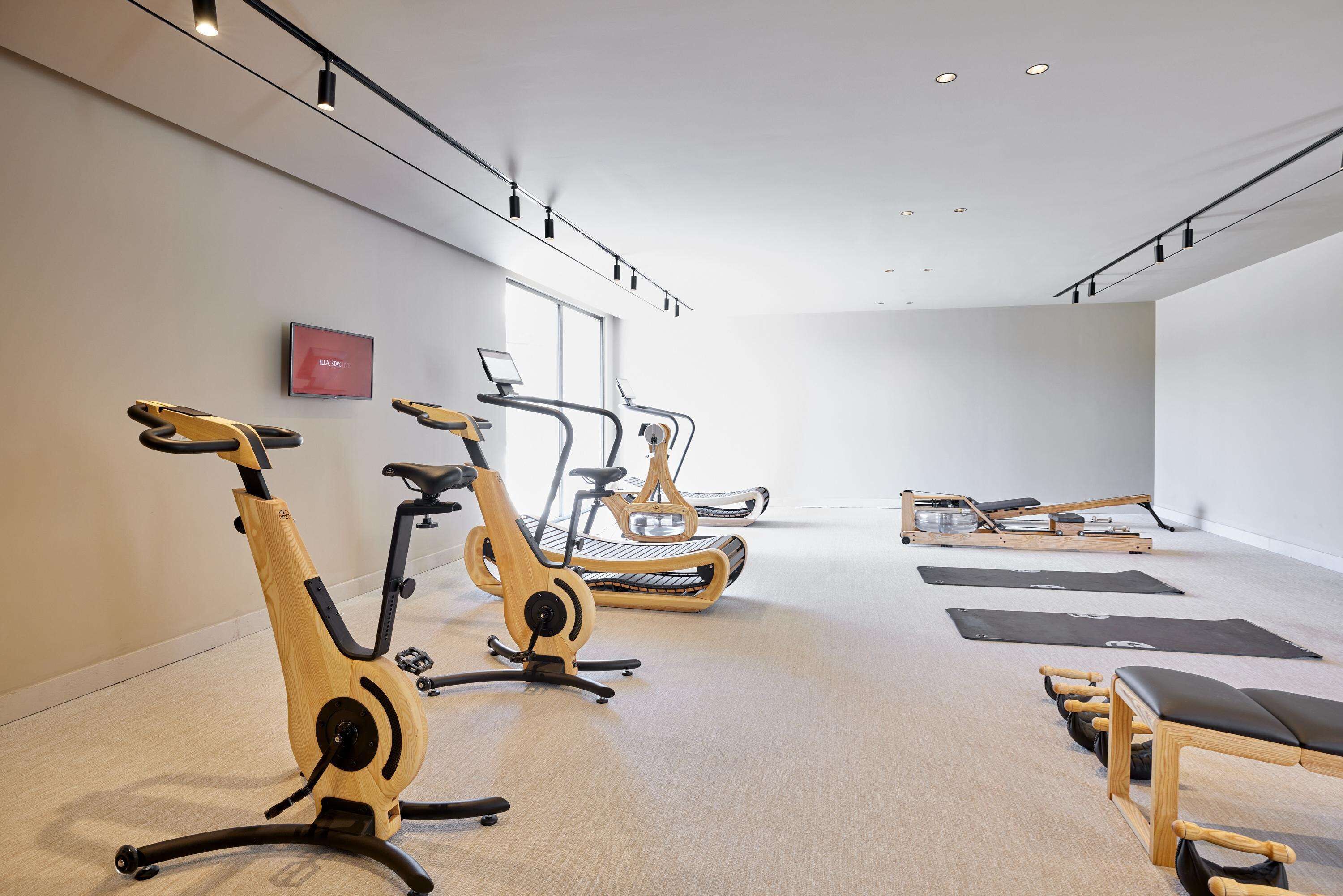 A fitness room with stationary bikes, treadmills, and a massage table.