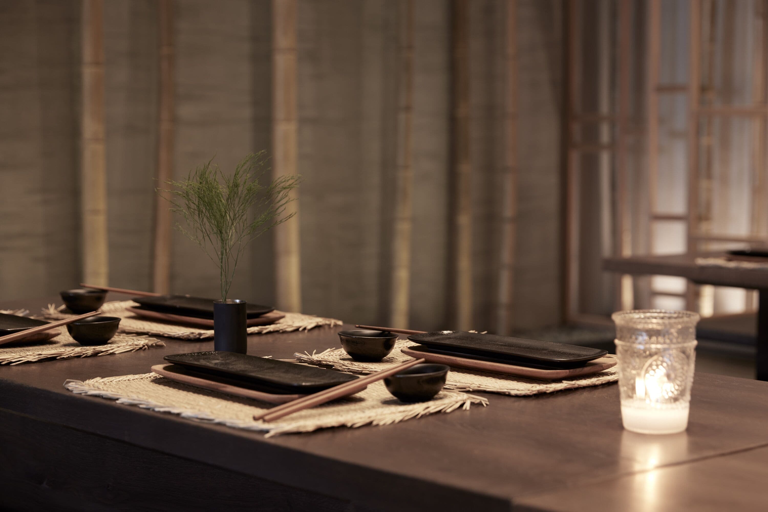 Una disposición tradicional para comer japonesa, con esteras de tatami, palillos y una vela.