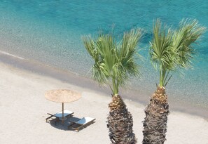 A beach with two palm trees, a beach umbrella, and a lounge chair. - Ella Elissa – Adults Only (Rhodes)