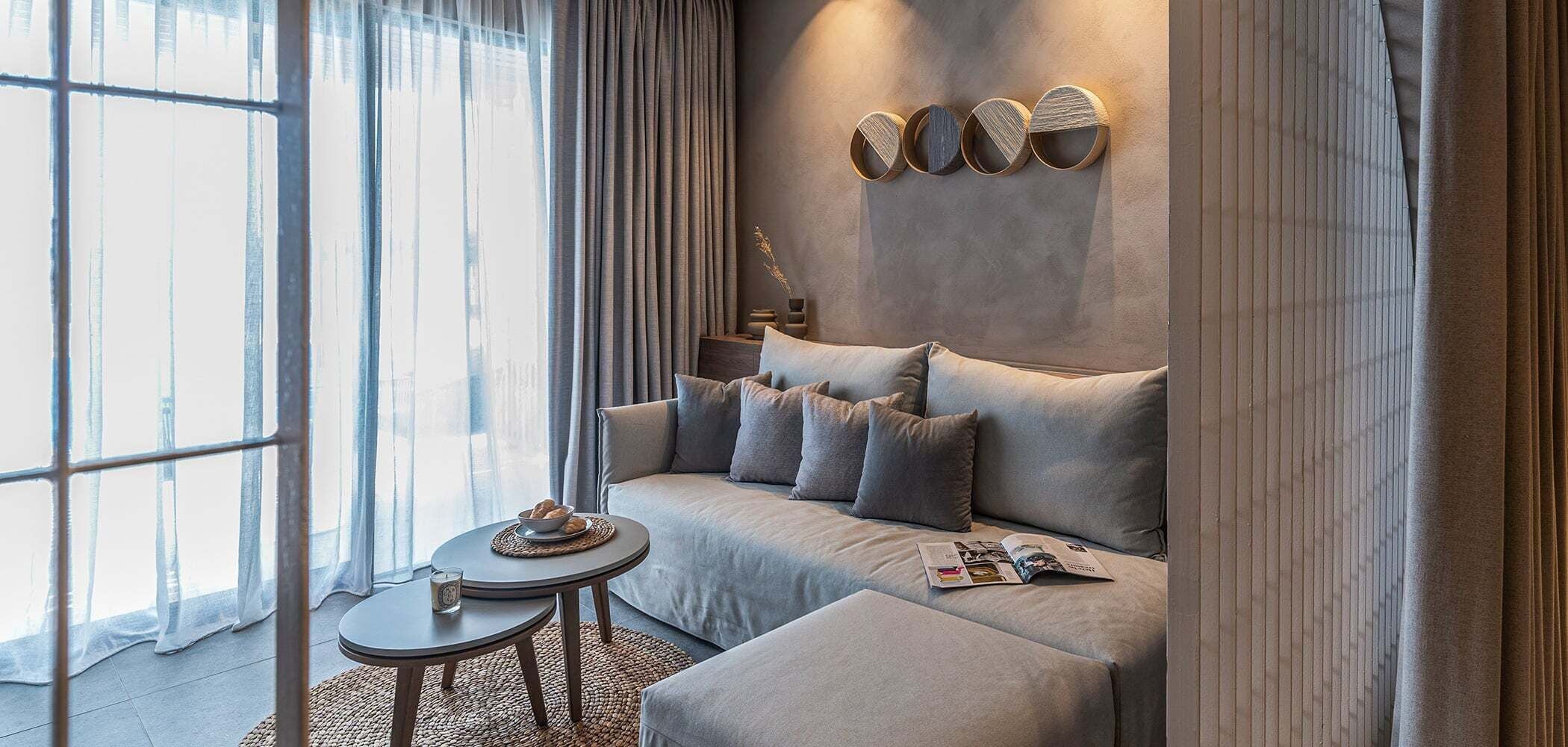 A modern living room with a sofa, a small round table, and a decorative wall piece.