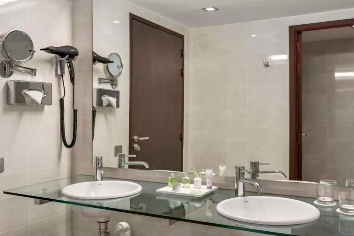 Une salle de bain moderne avec deux vasques, un plan de toilette en verre et un grand miroir.