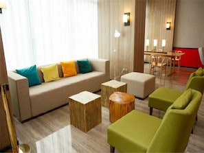 Una sala de estar moderna con un sofá, otomanas y sillones. Hay un comedor con una mesa y sillas.