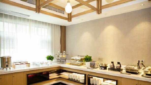A modern kitchen with wooden cabinets, a built-in oven, and a variety of appliances. - Jinjiang Metropolo Hotel (Hangzhou Huanglong Sports Center Wensan Road Subway Station Branch) (Hangzhou)