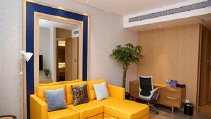 A modern hotel room with a yellow sofa, a desk, a chair, and a large mirror. - Jinjiang Metropolo Hotel (Hangzhou Huanglong Sports Center Wensan Road Subway Station Branch) (Hangzhou)