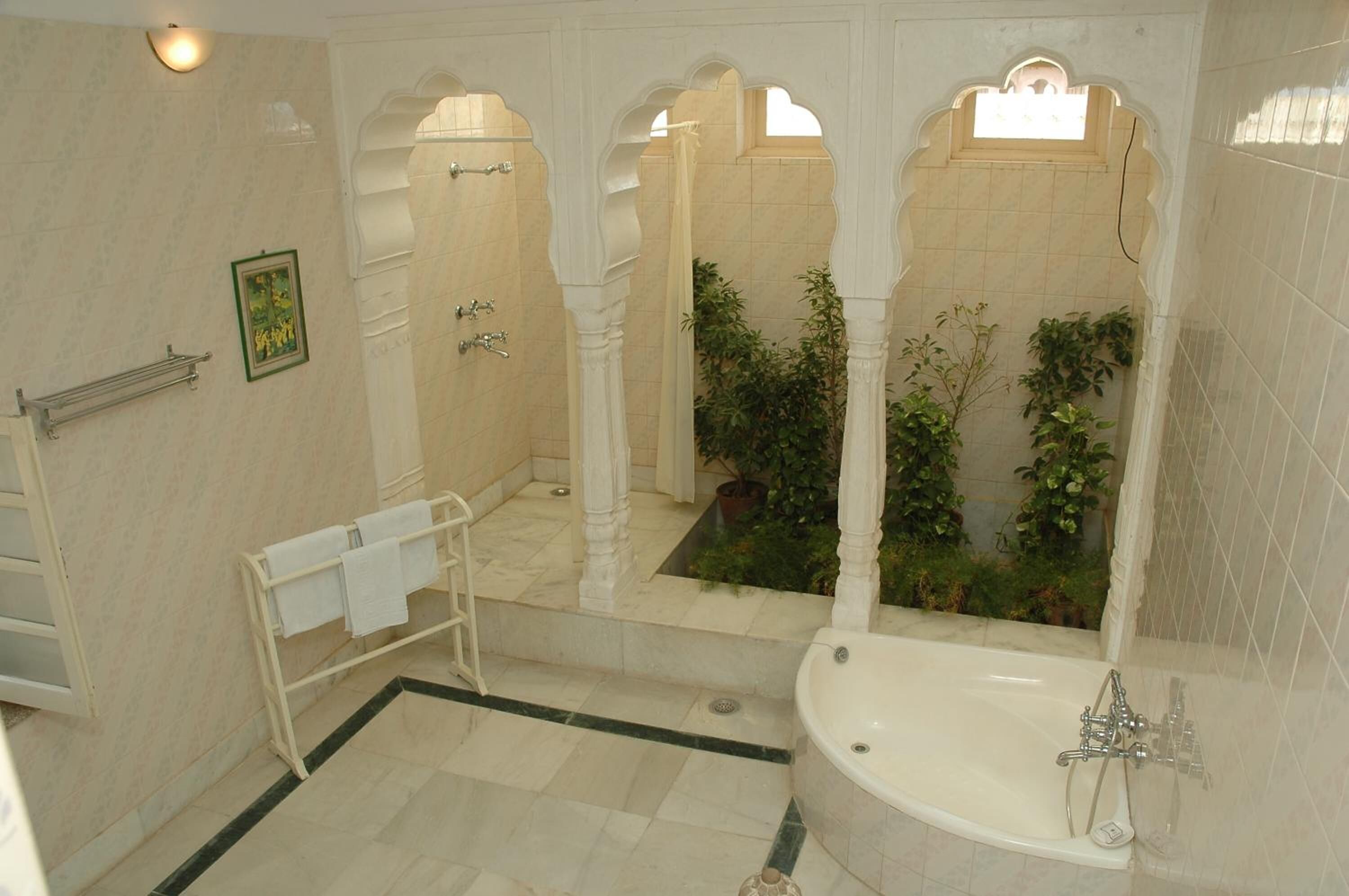 A bathroom with a bathtub, a towel rack, and a small potted plant.