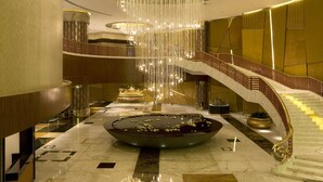 A grand lobby with a central water feature, a grand staircase, and a large chandelier. - Grand Lisboa Macau (Macau)