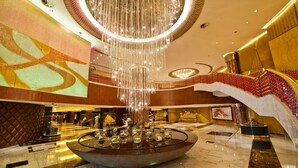 A luxurious lobby with a central circular water feature, a grand chandelier, and a red and gold staircase. - Grand Lisboa Macau (Macau)