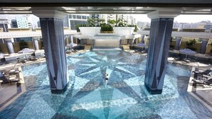 A rooftop pool with a central waterfall, surrounded by lounge chairs and potted plants. - Grand Lisboa Macau (Macau)