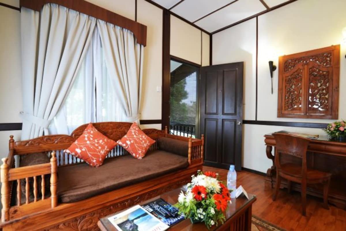 A traditional Japanese-style room with tatami flooring, a low wooden sofa with cushions, a wooden desk, and a shoji screen door.