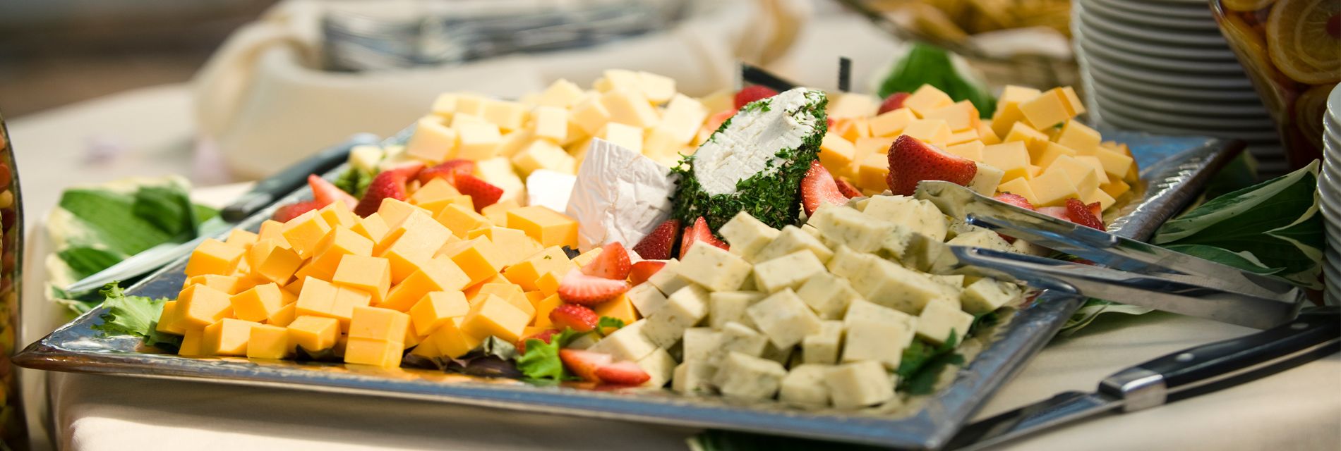 A buffet with various cheeses and fruits.