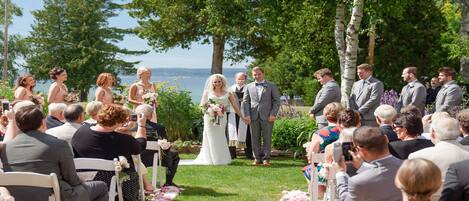 A wedding ceremony outdoors with guests seated on chairs facing the couple.