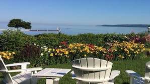 A garden with Adirondack chairs and a view of a lake. - Bay View Inn (Petoskey)