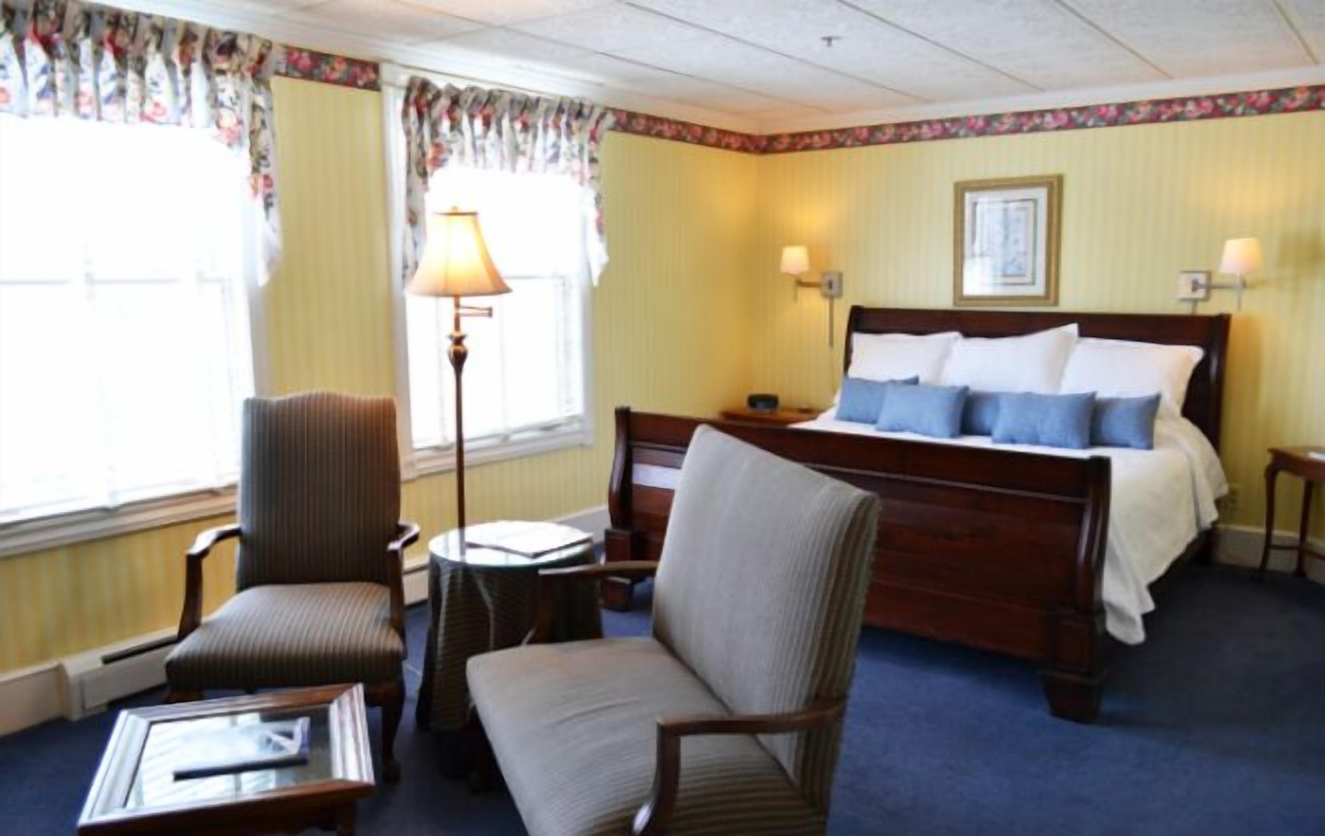 Een hotelkamer met een bed, twee stoelen, een kleine tafel en een lamp.