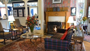 A traditional living room with a fireplace, patterned rug, and classic furniture. - Bay View Inn (Petoskey)
