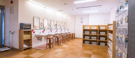 Ein sauberes, gut beleuchtetes öffentliches WC mit mehreren Waschbecken, Holzschemeln und Ablageflächen.