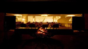An indoor setting with a central fire feature, tables, and chairs arranged for dining or socializing. - Naeba Prince Hotel (Yuzawa)