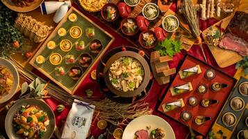 A variety of dishes and food items arranged on a table, including pasta, a pie, and several small bowls with different foods.