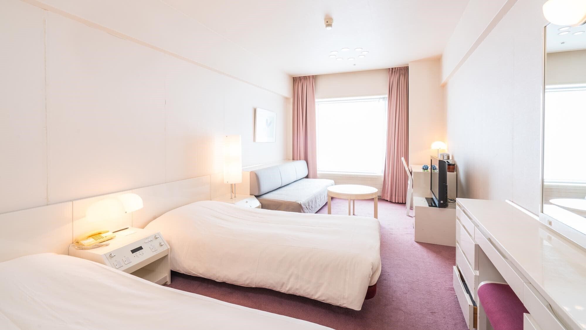 A hotel room with two beds, a desk, a chair, a TV, and a window with curtains.