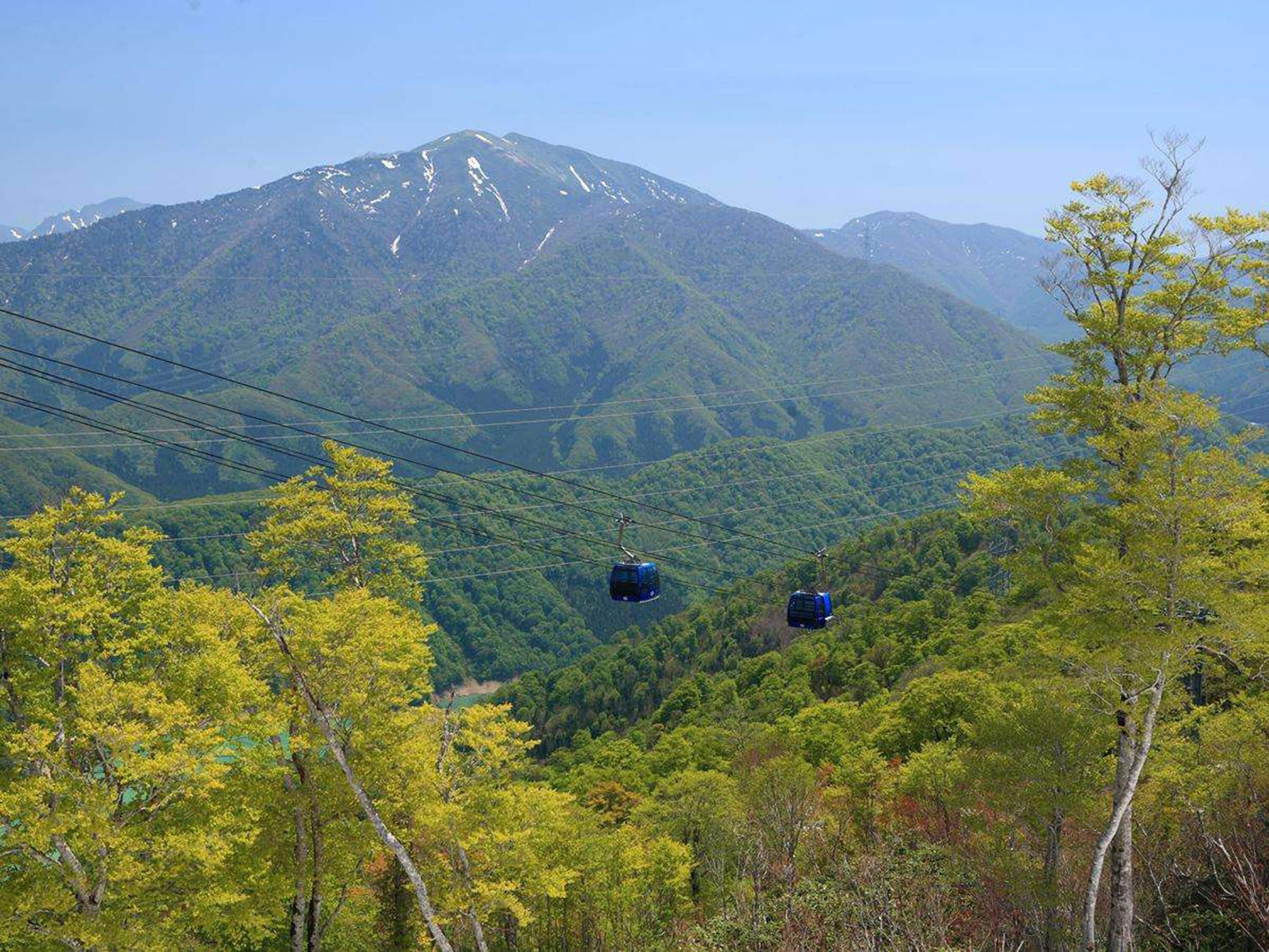 A mountain landscape with cable cars in the foreground and a clear sky.