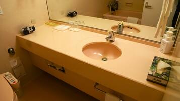 A bathroom with a beige sink, mirror, and a towel rack.