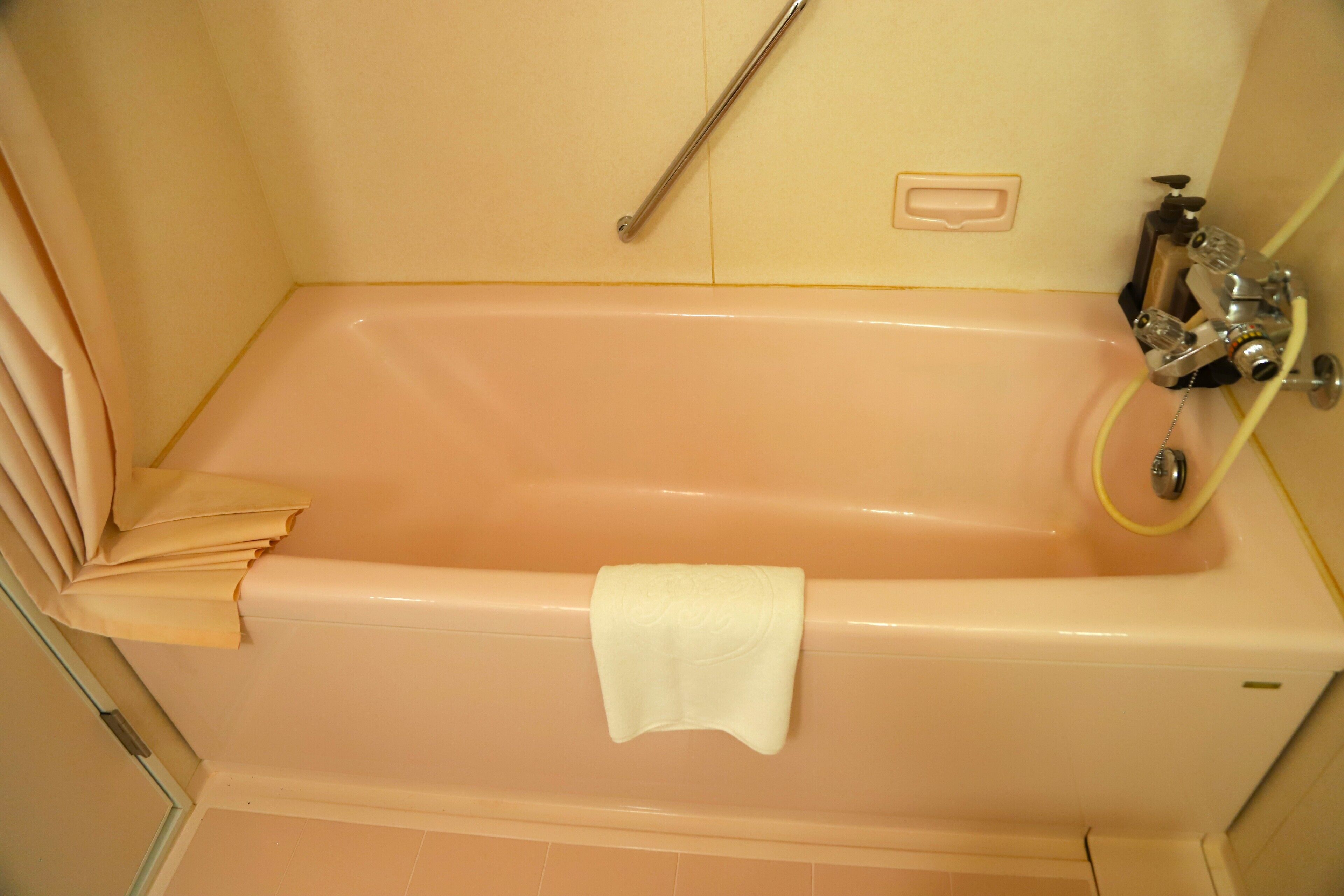 A bathroom with a bathtub, a towel rack, and a showerhead.