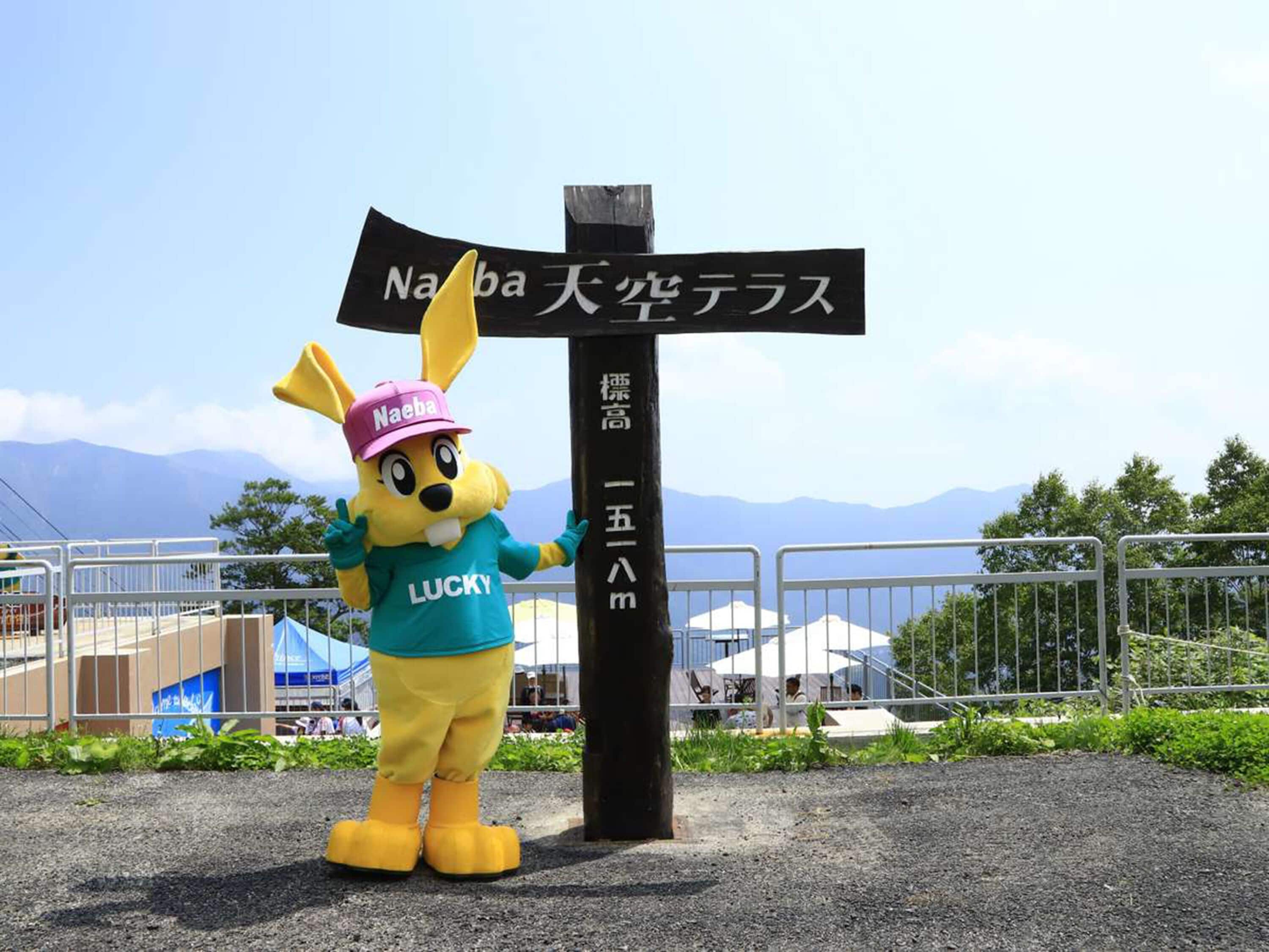 A mascot standing next to a signpost with Japanese text.