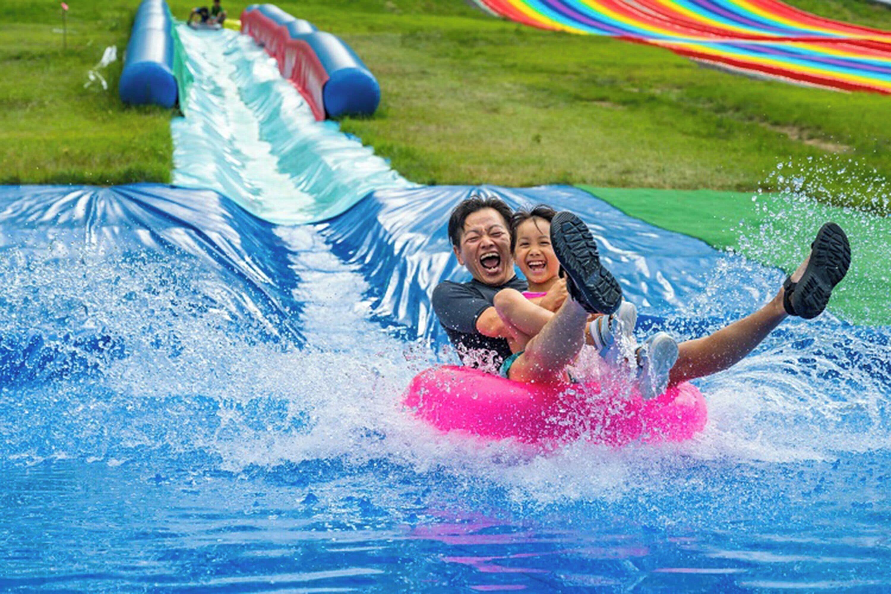Un toboggan aquatique avec des bouées gonflables et un décor en tissu aux couleurs de l’arc-en-ciel.