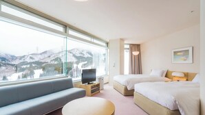 A hotel room with a large window, a sofa, two beds, a TV, and a small table. - Naeba Prince Hotel (Yuzawa)