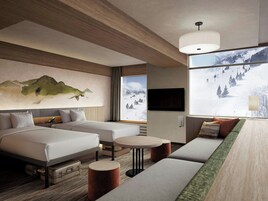 A modern hotel room with a large bed, a sofa, a small table, and a TV.