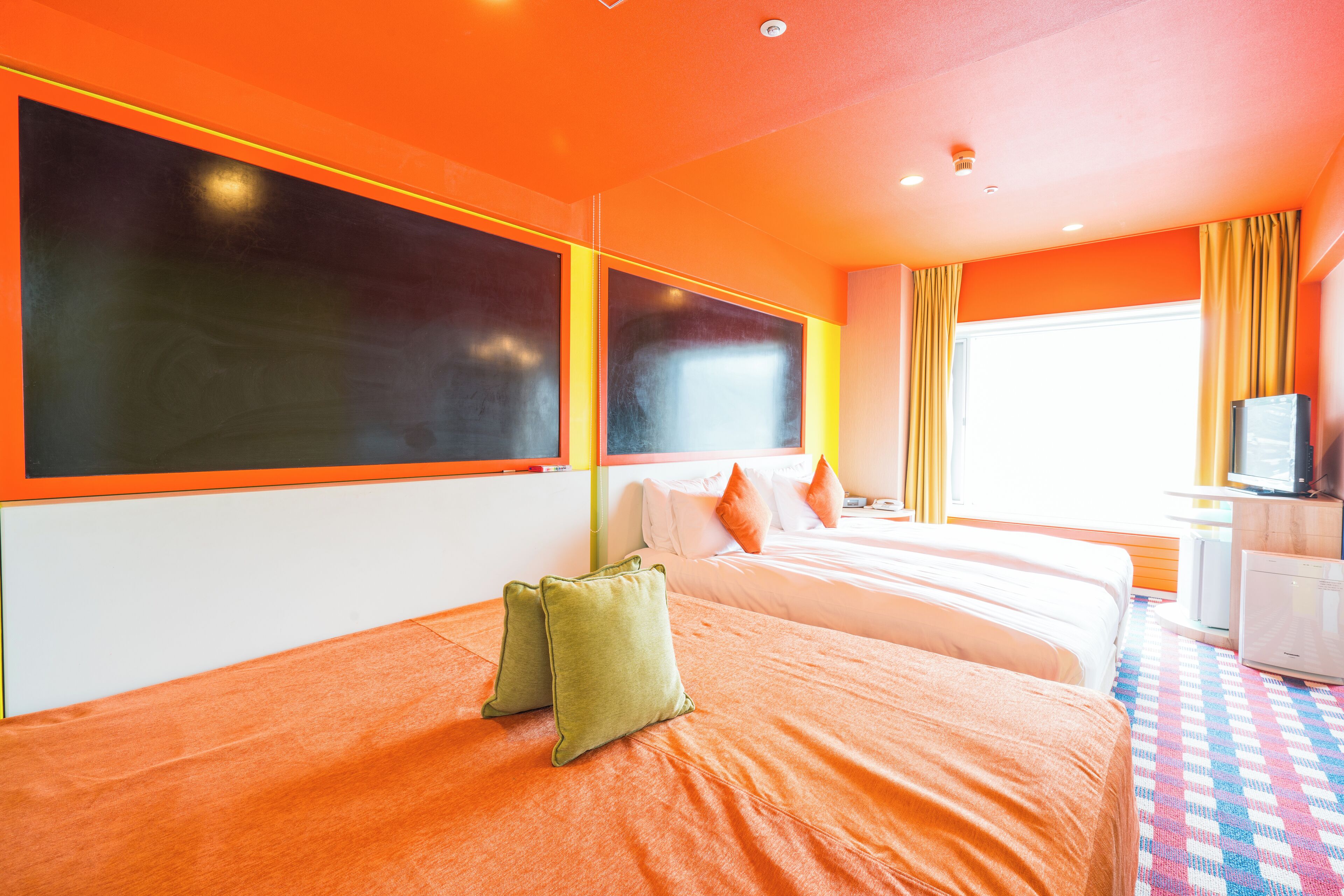 A hotel room with two beds, a large window, and a television.