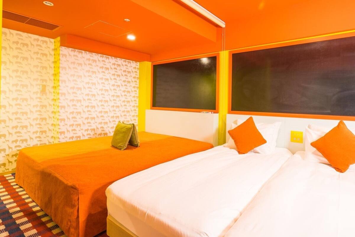 A hotel room with two beds, a patterned wallpaper, and a check-in station.