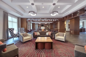 A spacious lobby with a central seating area, a bar, and a view of the dining area.
