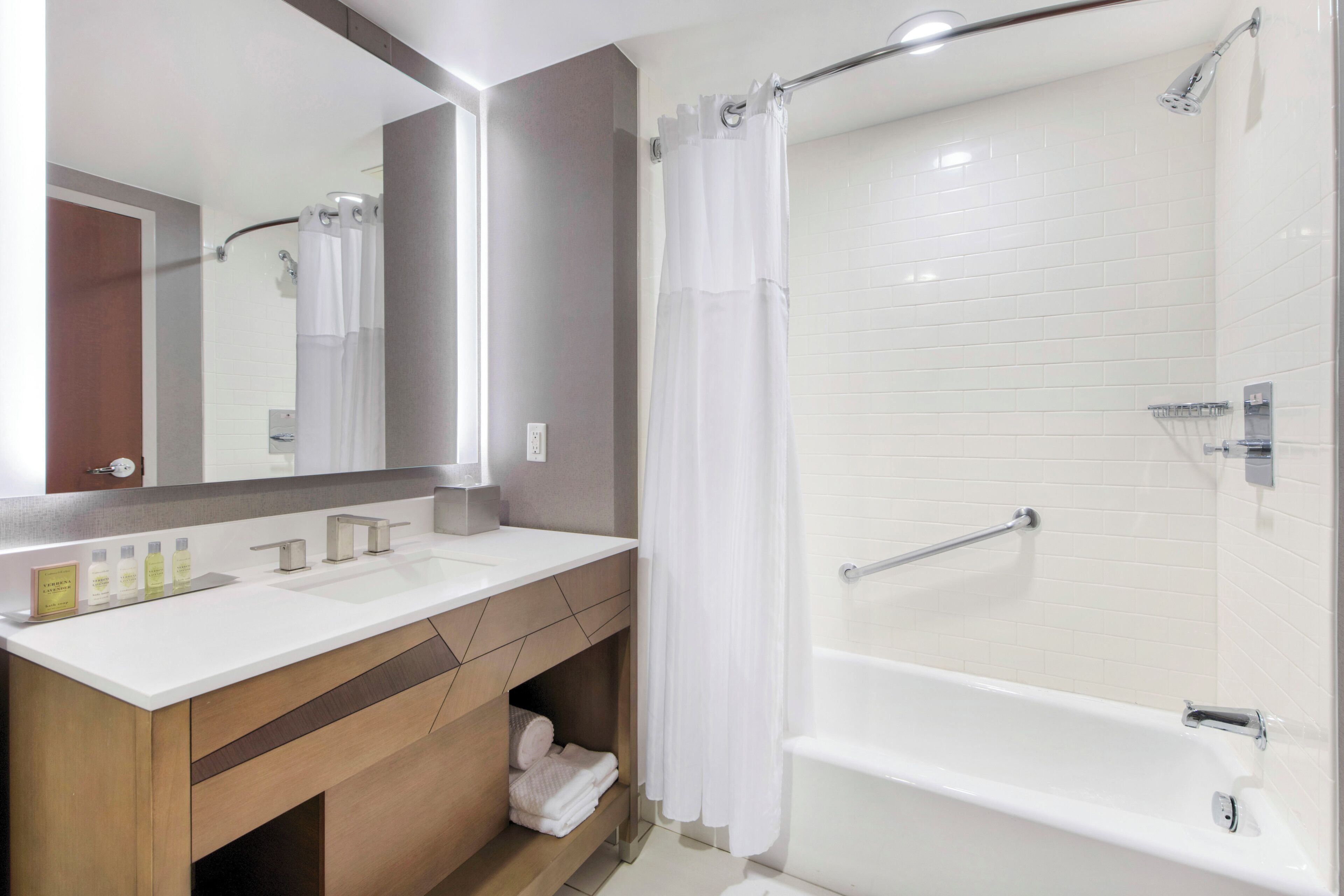 A modern bathroom with a double sink vanity, a shower with a glass door, and a large mirror.